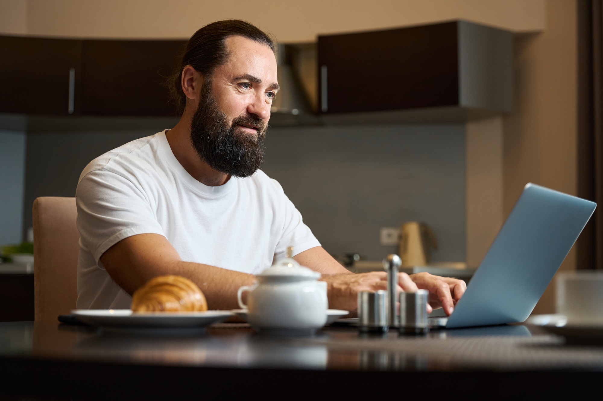 Businessman communicates by laptop during breakfast